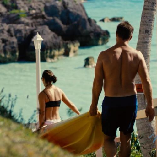 a man and a woman walking on the beach with a surfboard at Willowbank Resort in Somerset