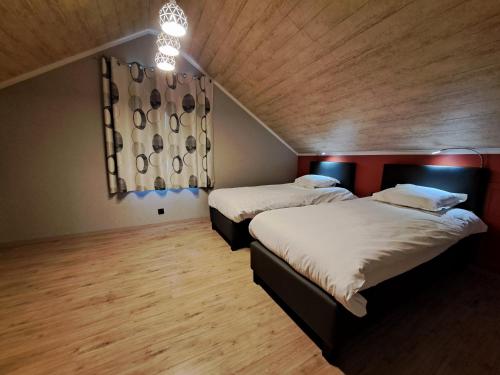 two beds in a room with a wooden ceiling at Chanteloup, Maison d'hotes - Halleux in Halleux