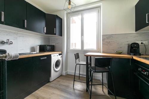 a kitchen with black cabinets and a washer and dryer at Le nid des Ducs in Dijon