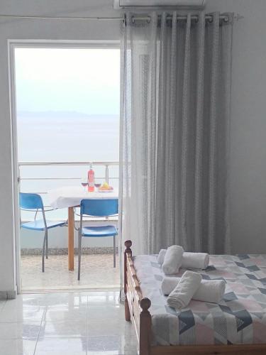 a bedroom with a bed and a table and a window at NaDim rooms in Himare