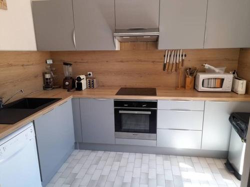 une cuisine avec des armoires blanches et un micro-ondes dans l'établissement Appart 1403, Tennis village, au Cap d'Agde