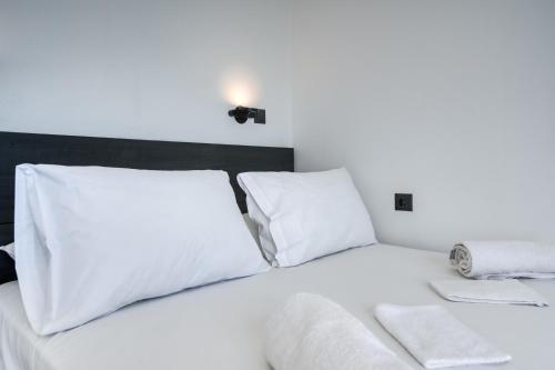 a white bed with white sheets and pillows at Akrogiali Apartments in Barbati