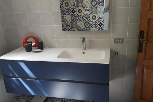 ein Badezimmer mit einem weißen Waschbecken und einem Spiegel in der Unterkunft Grande villa con piscina privata in Maruggio