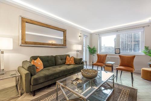 sala de estar con sofá verde y mesa de cristal en Flat 5, en Londres