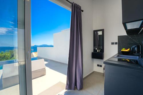 a kitchen with a purple curtain and a view of the ocean at Akrogiali Apartments in Barbati