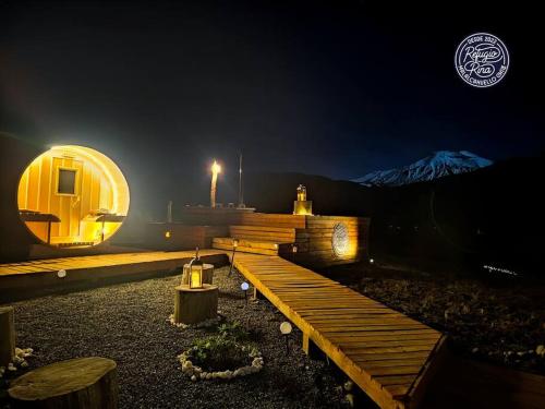 a small building with a wooden deck at night at Confortable refugio de monataña con vista al Volcan in Malalcahuello