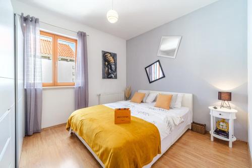 a bedroom with a bed with a yellow blanket on it at Guest house Barbara in Nerežišća