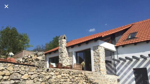 una pared de piedra junto a una casa con un edificio en Casa cu piscina Cheile Nerei, en Socolari