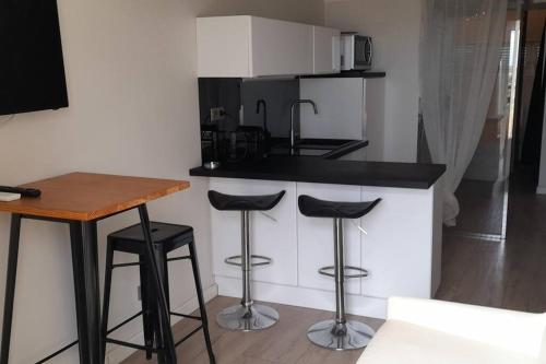 une cuisine avec deux tabourets de bar et un comptoir dans l'établissement Appart 373, Port Nature 3 au village naturiste, au Cap d'Agde