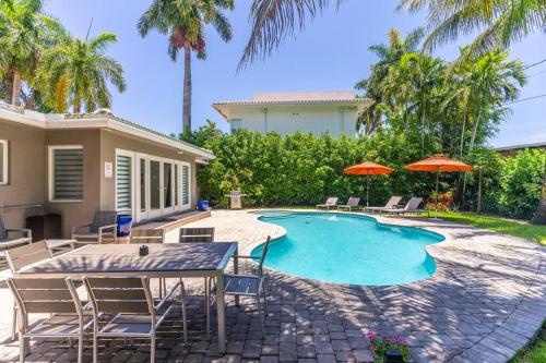 a swimming pool with chairs and a table and umbrellas at Luxury 3 Bedroom Home 5 minutes to Ocean with Heated Pool in Hollywood