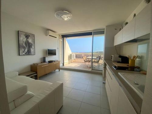 Il comprend une cuisine et un salon avec une grande fenêtre. dans l'établissement Appart 408, Héliopolis K au village naturiste, au Cap d'Agde