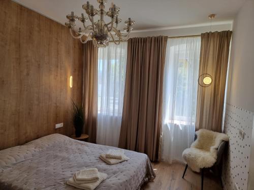 1 dormitorio con cama, lámpara de araña y silla en Apartma Larisa, en Bled