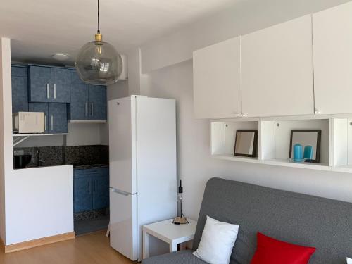 ein Wohnzimmer mit einem Sofa und einem weißen Kühlschrank in der Unterkunft Estudio Granada in Nerja