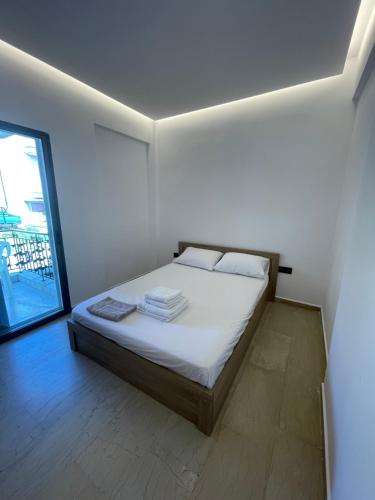 a bedroom with a bed with white sheets and a window at Ntina's Room in Nea Potidaea