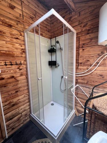 a shower in a room with a wooden wall at Urocza chatka w lesie nad wodą in Skubianka