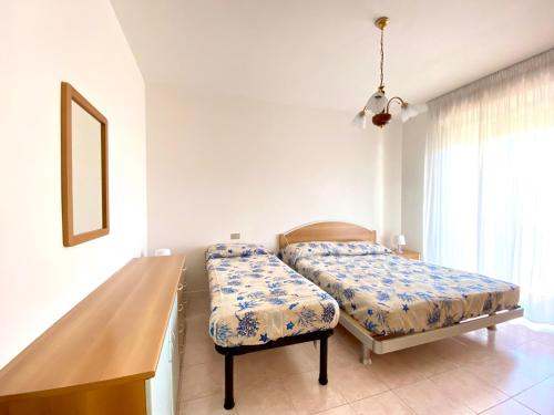 een slaapkamer met een bed, een bank en een raam bij Residence Cristoforo Colombo - Carraro Immobiliare - Family Apartments in Caorle