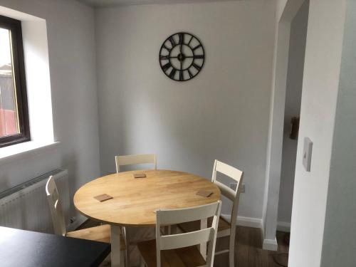 a dining room table with chairs and a clock on the wall at Moray View, Macduff, Aberdeenshire. in Macduff