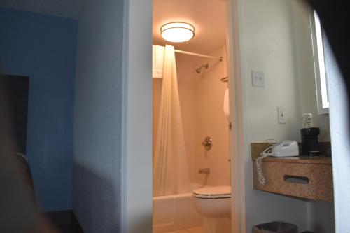 La salle de bains est pourvue de toilettes, d'une douche et d'une lumière. dans l'établissement Super 8 by Wyndham Riverside AL, à Riverside