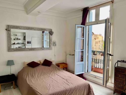 une chambre avec un lit et une grande fenêtre dans l'établissement La charmante maison aux volets bleu - Montpellier, à Montpellier