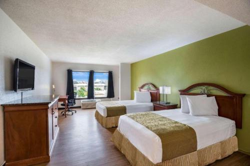 Habitación de hotel con 2 camas y TV de pantalla plana. en OYO Hotel Orlando Airport, en Orlando