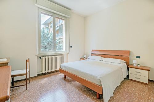 a white bedroom with a bed and a window at Clelia Apartments in Parma