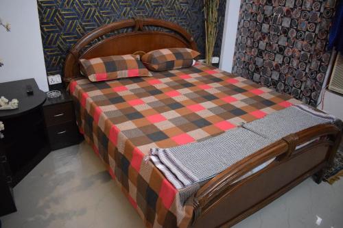 a bed with a checkered blanket and pillows on it at The Nest (Aura) your second home in Ghaziabad