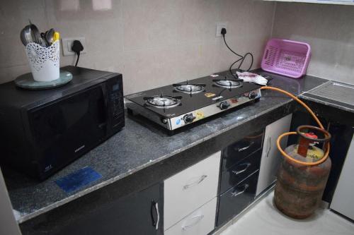 a kitchen with a stove and a microwave at The Nest (Aura) your second home in Ghaziabad