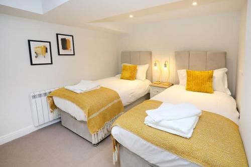 a bedroom with two beds with yellow pillows on them at Central Ripon apartment - view of the Cathedral! in Ripon