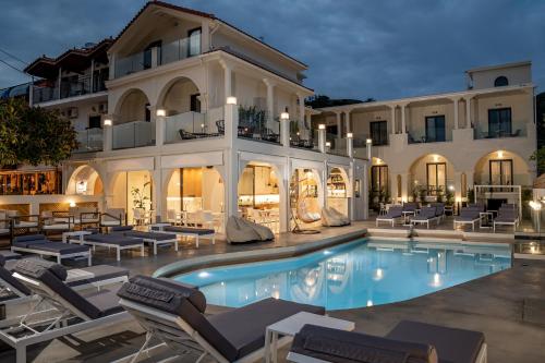 eine Villa mit einem Pool und Liegestühlen in der Unterkunft Nikon Boutique Hotel in Kalamaki