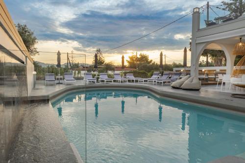 a swimming pool with white chairs and a building at Nikon Boutique Hotel in Kalamaki
