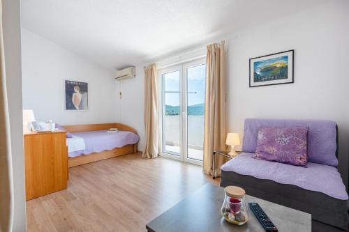 a bedroom with a bed and a couch and a table at Studio APARTMANI LEŽENIĆ in Neum