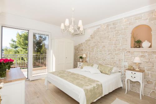 a white bedroom with a stone wall and a bed at La Perla in Cavtat