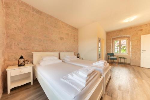 Duas camas brancas num quarto com pisos em madeira em Joe em Čilipi
