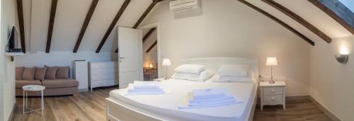a bedroom with a white bed and a couch at Joe in Čilipi