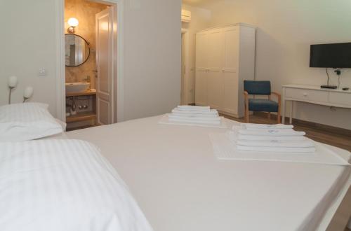 a white bed with a pile of towels on it at Joe in Čilipi