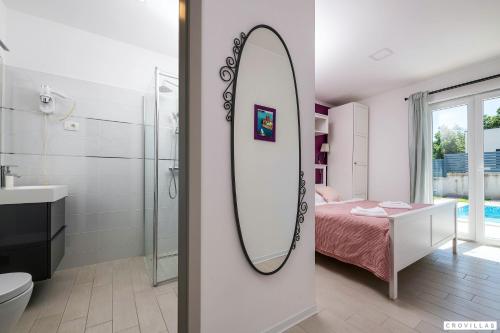 a bathroom with a mirror and a bedroom with a bed at Lavanda-labin in Veli Turini