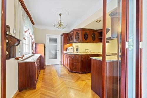 a kitchen with wooden cabinets and a wooden floor at Villa Muusa with a cozy sauna, swimming pool and large beautiful garden in Tallinn