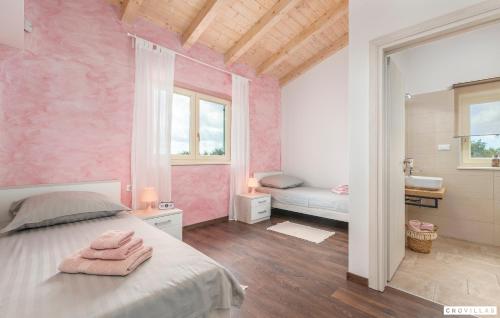 una camera da letto con pareti rosa, un letto e un bagno di Matea a Marčana