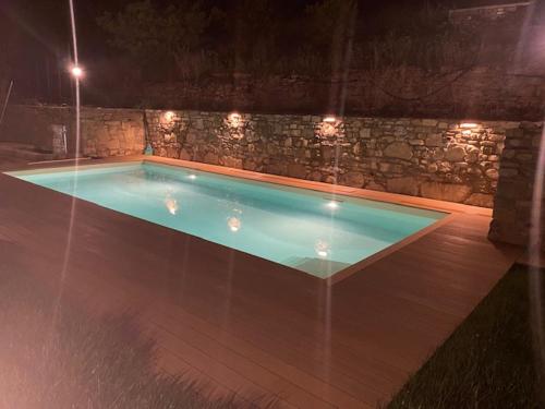 ein Schwimmbad in der Nacht mit einer Steinmauer in der Unterkunft Gli Orti dei Doria di dolceacqua in Dolceacqua