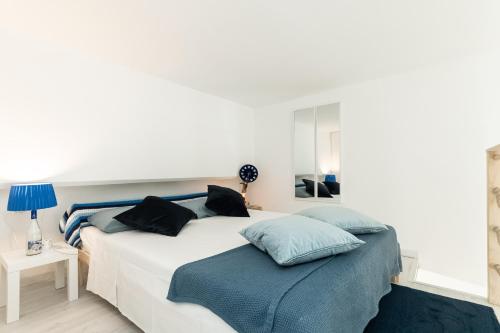 a bedroom with a white bed with blue pillows at Sea Loft Quinto - A due passi dal mare in Genova