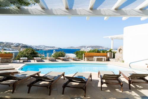 a swimming pool with tables and chairs next to a building at Rhenia Hotel in Tourlos