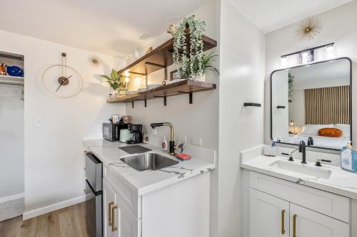 uma cozinha branca com um lavatório e um espelho em Bright & Cozy Condo Unit with Balcony! em Honolulu
