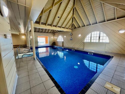a large swimming pool with blue water in a building at Holly Tree Hotel, Swimming Pool & Hot Tub in Glencoe