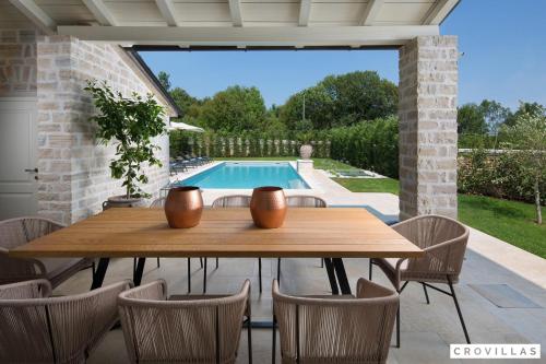 a patio with a wooden table and chairs and a pool at Zoe in Ladići