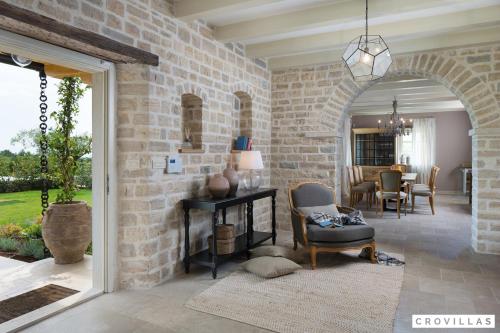 a living room with a stone wall with a chair and a fireplace at Zoe in Ladići