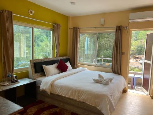 a bedroom with a large bed with two windows at Hotel Village View Nagarkot in Nagarkot