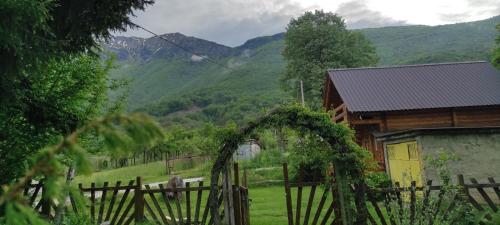 a wooden house with a fence and mountains in the background at Velemun brvnara in Plav