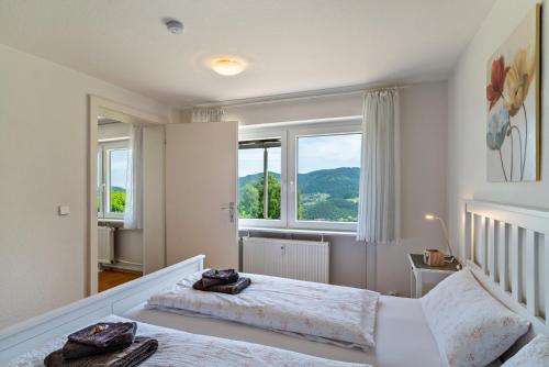 a bedroom with two beds and two windows at Merzel's schöne Aussicht in Bühlertal