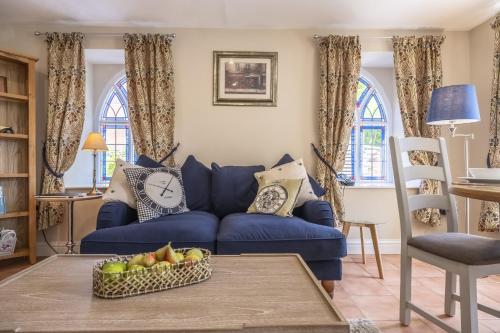 a blue couch in a living room with a bowl of fruit at The Clockhouse in North Lopham
