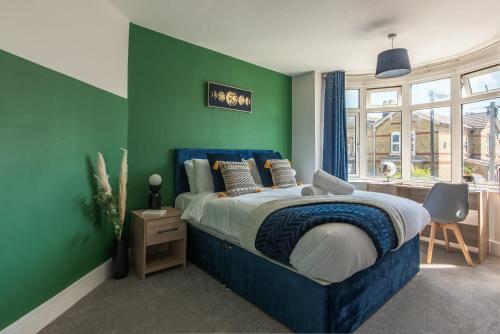 a bedroom with a blue bed and a green wall at Spacious Southampton House Sanctuary in the City in Southampton